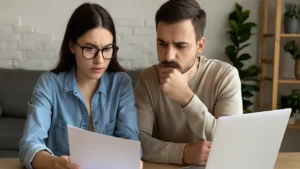 Kobieta i mężczyzna analizują oferty ubezpieczenia samochodu przy stole z laptopem i dokumentami